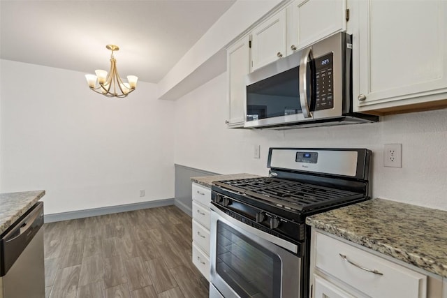 3411 Thomas Kincheon St, Austin, TX 78745 - kitchen with appliances with stainless steel finishes, a chandelier, white cabinetry, light stone counters, and decorative light fixtures
