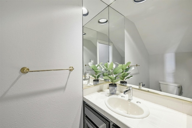 bathroom featuring lofted ceiling, vanity, and toilet