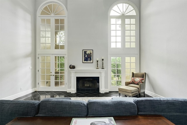 living room with a high ceiling, a fireplace, and french doors