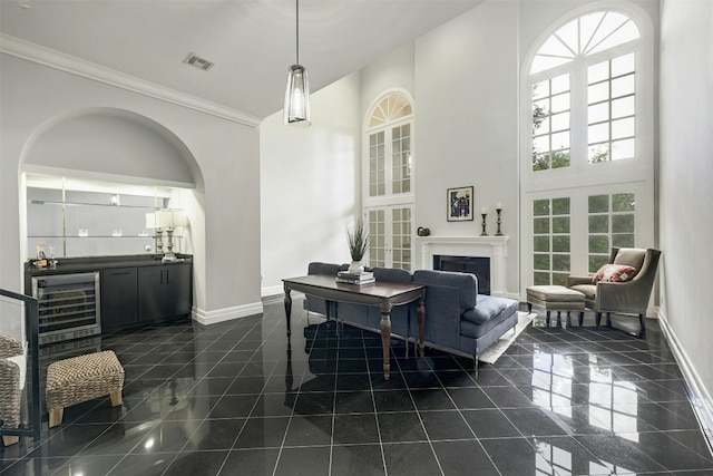 living room with ornamental molding, beverage cooler, a high ceiling, and bar area