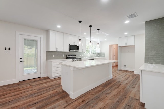 kitchen with white cabinetry, stainless steel appliances, a center island, backsplash, and dark wood-type flooring