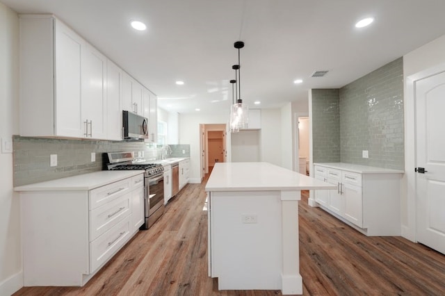 kitchen featuring wood-type flooring, white cabinets, and stainless steel appliances