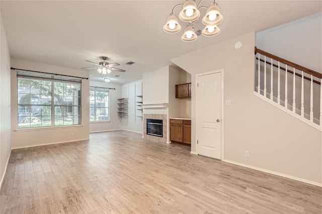 unfurnished living room featuring light wood-type flooring, baseboards, ceiling fan with notable chandelier, and a fireplace