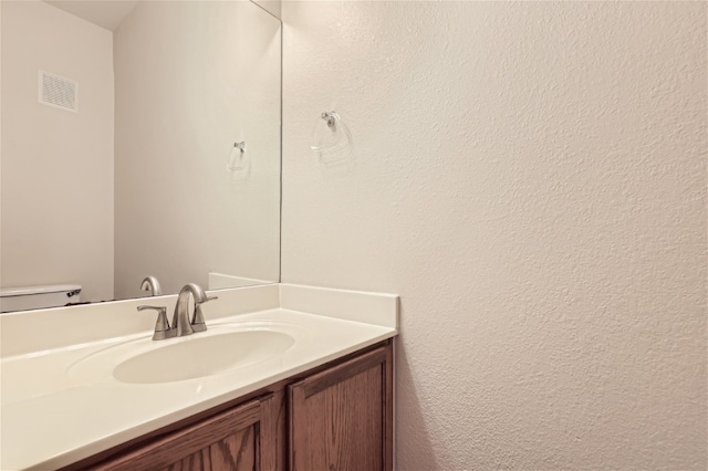 bathroom featuring toilet, visible vents, and vanity