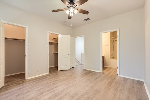 unfurnished bedroom with light hardwood / wood-style flooring, a spacious closet, ceiling fan, ensuite bath, and a closet