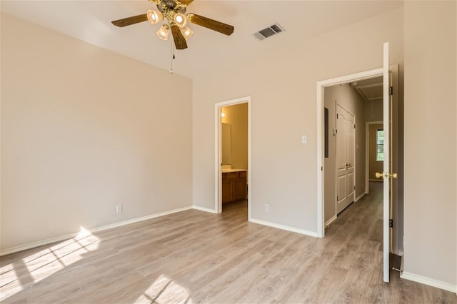 unfurnished bedroom featuring attic access, baseboards, ensuite bathroom, light wood-type flooring, and visible vents