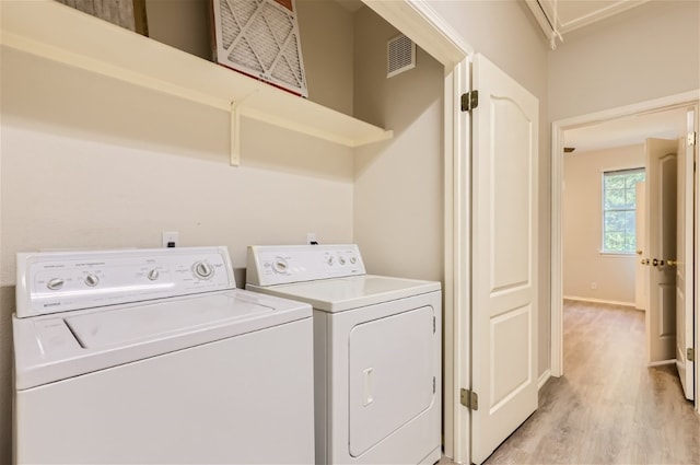 laundry room with washer and dryer and light wood-type flooring