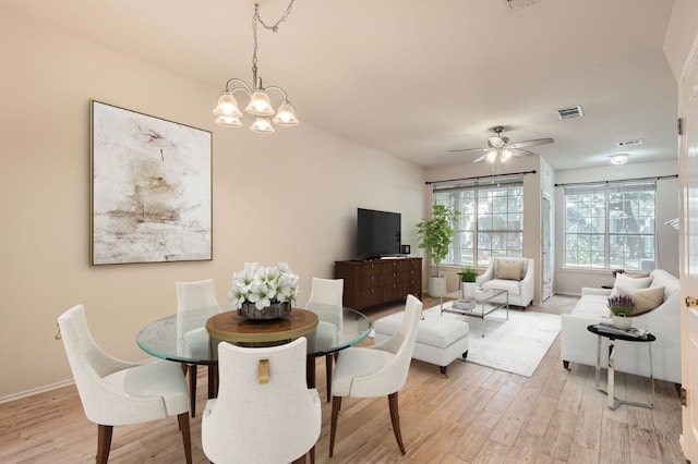 dining room with ceiling fan with notable chandelier and light hardwood / wood-style flooring