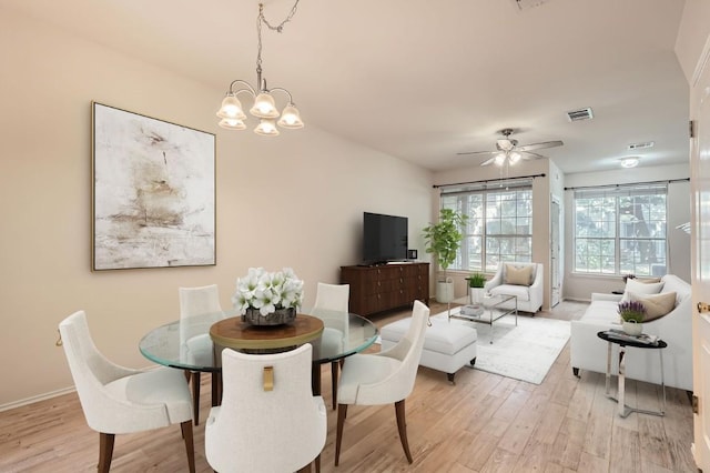 dining space with visible vents, ceiling fan with notable chandelier, and light wood-type flooring