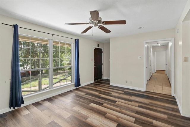 spare room featuring wood finished floors, a ceiling fan, and baseboards