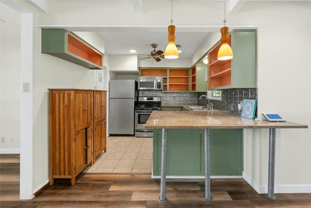 kitchen featuring open shelves, backsplash, appliances with stainless steel finishes, a sink, and a peninsula