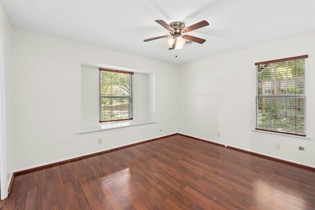 empty room with wood finished floors, a ceiling fan, and baseboards