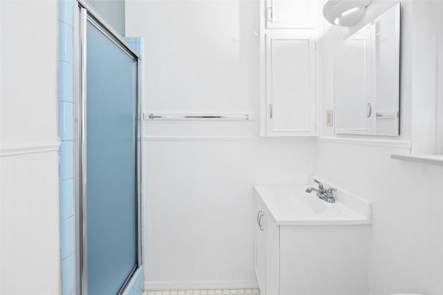 bathroom with a wainscoted wall, a shower with door, and vanity