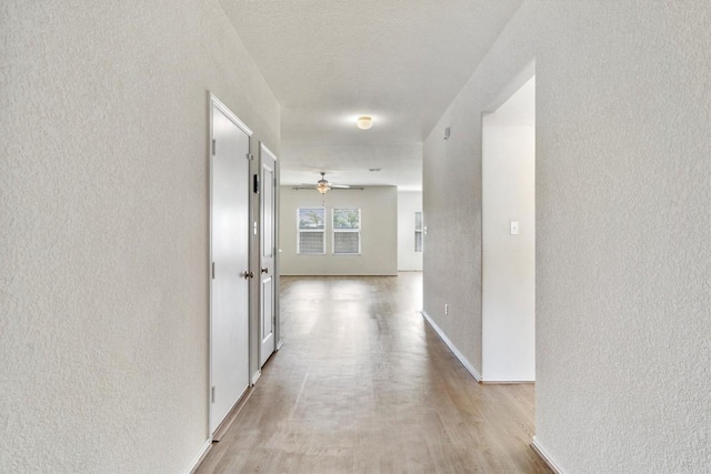 hall with light hardwood / wood-style floors and a textured ceiling