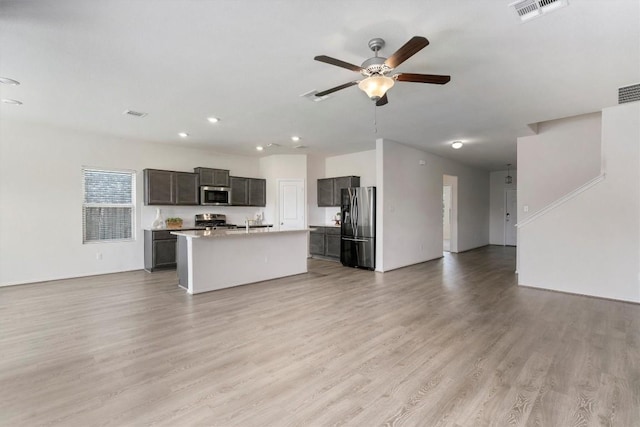 kitchen featuring a kitchen island with sink, ceiling fan, light hardwood / wood-style floors, and appliances with stainless steel finishes