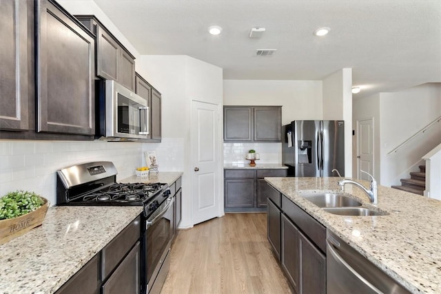 kitchen with appliances with stainless steel finishes, tasteful backsplash, light stone counters, and sink