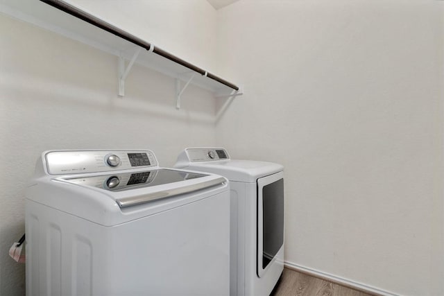 clothes washing area with washer and dryer and light wood-type flooring