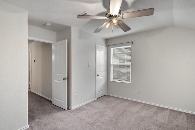 unfurnished bedroom with a textured ceiling, ceiling fan, lofted ceiling, and light carpet