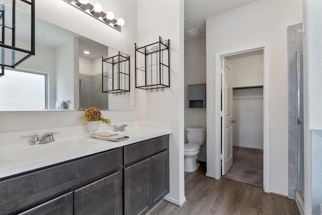 bathroom with hardwood / wood-style floors, vanity, toilet, and a shower with shower door