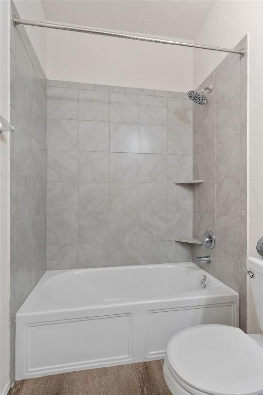 bathroom featuring toilet and tiled shower / bath