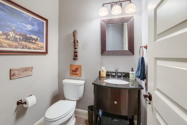 bathroom featuring toilet, wood-type flooring, and vanity