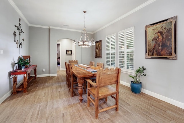 dining space with ornamental molding, light hardwood / wood-style floors, and an inviting chandelier