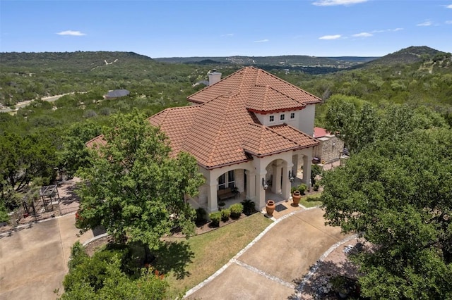 view of front of property featuring stucco siding, a mountain view, a chimney, and a tiled roof