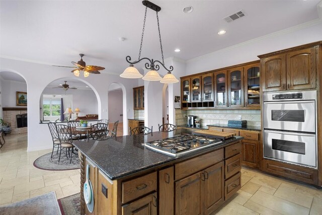 kitchen featuring tasteful backsplash, light tile patterned flooring, stainless steel appliances, and a center island