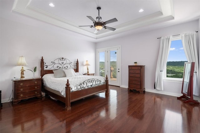 bedroom featuring ornamental molding, a tray ceiling, wood finished floors, baseboards, and access to exterior