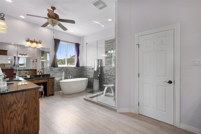 bathroom featuring visible vents, a shower stall, a freestanding bath, vanity, and tile walls