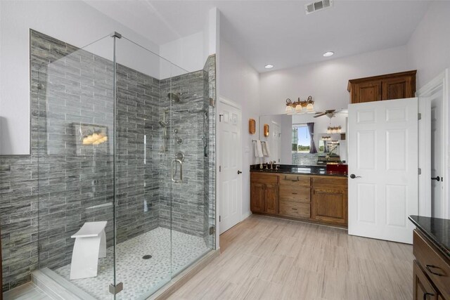 bathroom featuring a shower with shower door, ceiling fan, double sink vanity, and tile patterned flooring