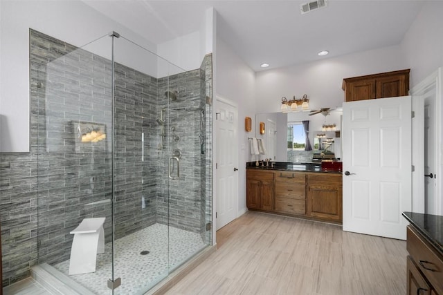 full bathroom featuring vanity, a shower stall, and visible vents