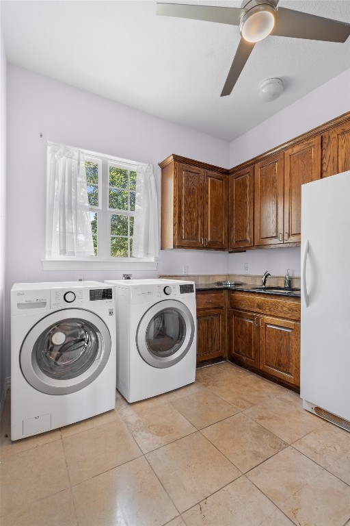 clothes washing area with cabinets, light tile patterned floors, ceiling fan, sink, and washing machine and clothes dryer