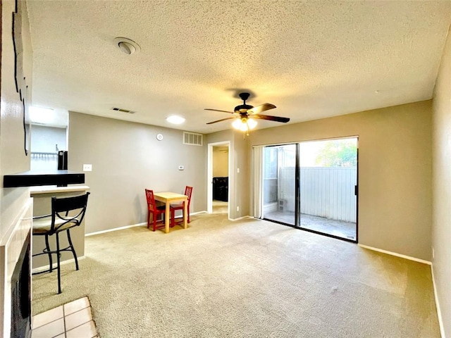 interior space with ceiling fan, light colored carpet, and a textured ceiling