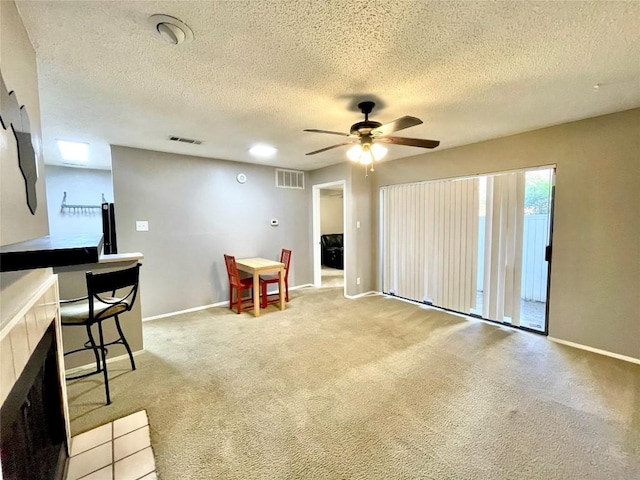 interior space featuring light carpet, a textured ceiling, and ceiling fan