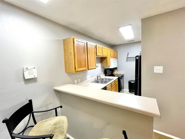 kitchen with sink, a breakfast bar area, kitchen peninsula, and black appliances