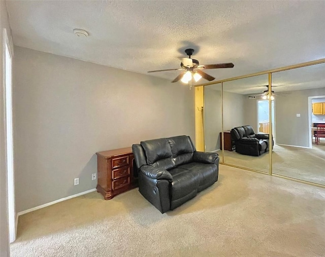 sitting room featuring ceiling fan, light colored carpet, and a textured ceiling