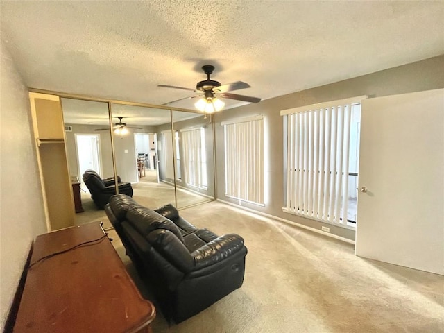 carpeted living room featuring ceiling fan and a textured ceiling