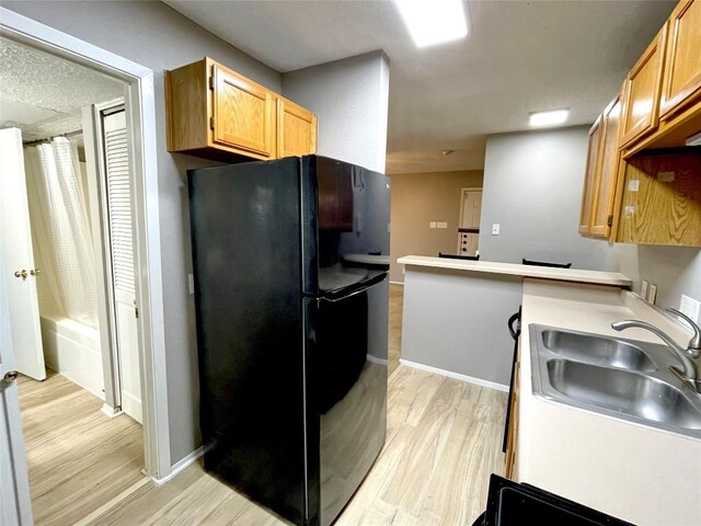 kitchen featuring black refrigerator, light hardwood / wood-style floors, and sink