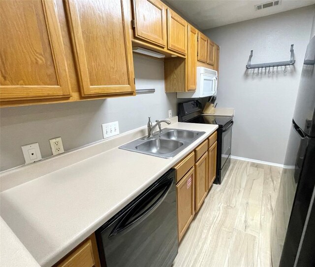 kitchen with sink, black appliances, and light wood-type flooring