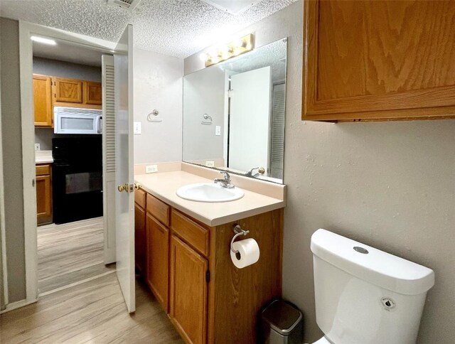 bathroom with vanity, hardwood / wood-style floors, toilet, and a textured ceiling