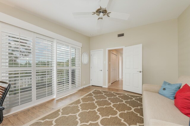 living area with a ceiling fan, baseboards, visible vents, and wood finished floors