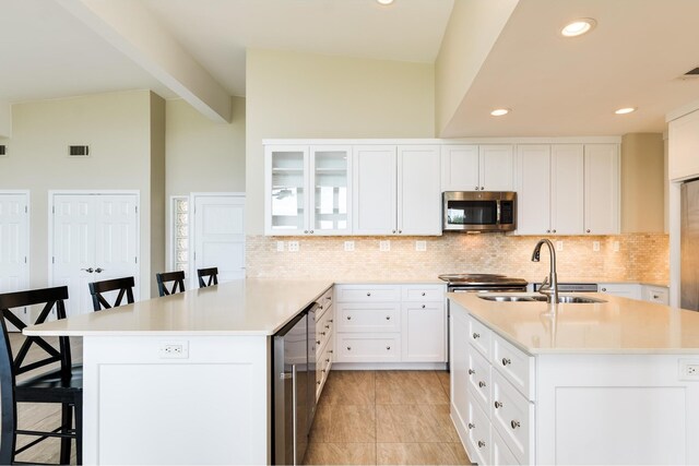 kitchen with glass insert cabinets, a breakfast bar area, light countertops, and stainless steel microwave