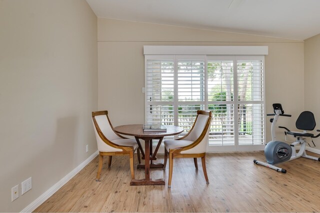 dining room with lofted ceiling, baseboards, and light wood finished floors