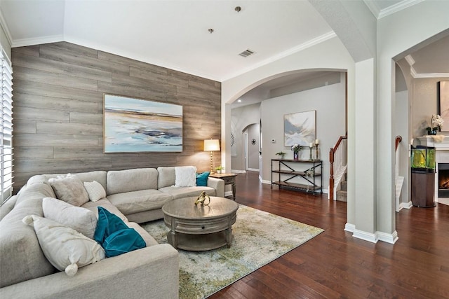 living room with dark hardwood / wood-style flooring, vaulted ceiling, and ornamental molding