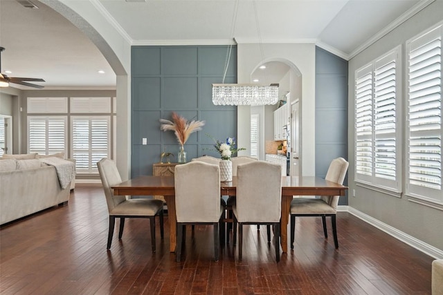 dining area with ceiling fan with notable chandelier, dark wood-type flooring, plenty of natural light, and ornamental molding