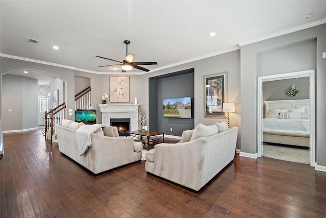 living room with a tile fireplace, ceiling fan, dark hardwood / wood-style floors, and ornamental molding