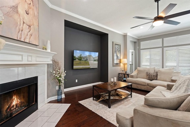 living room with a tile fireplace, crown molding, hardwood / wood-style floors, and ceiling fan