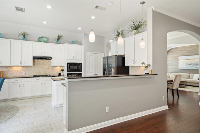 kitchen with black microwave, stainless steel fridge with ice dispenser, decorative light fixtures, decorative backsplash, and white cabinets