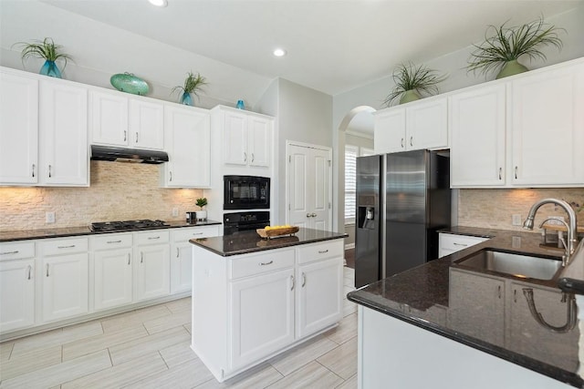 kitchen with white cabinetry, sink, dark stone counters, a kitchen island, and black appliances